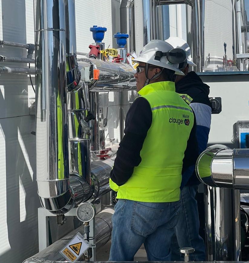 Two Clauger de Mexico employees are working on an outdoor refrigeration system.